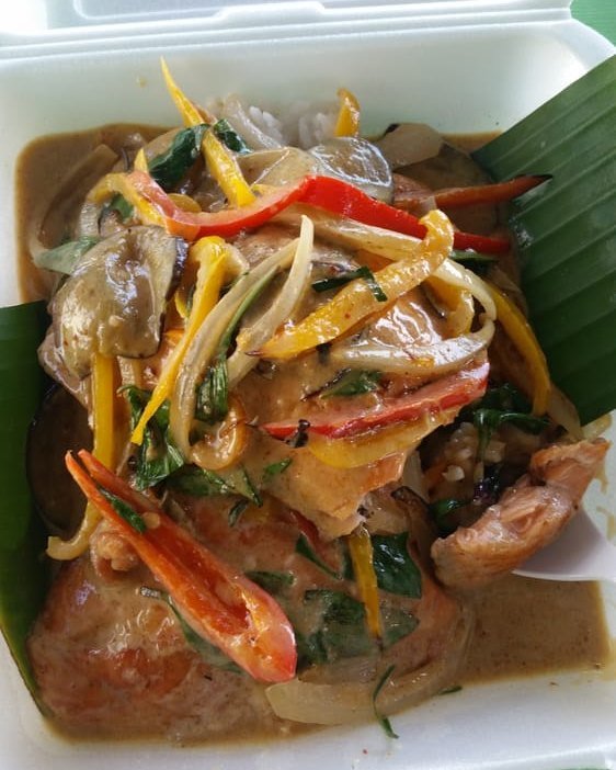Panang curry over rice on a banana leaf, with bell peppers and Thai basil