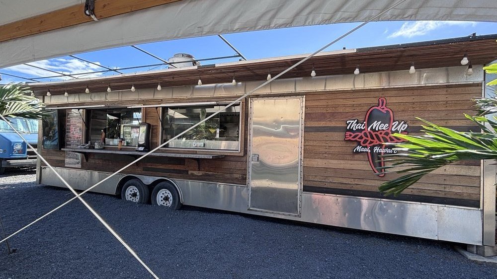 The Thai Mee Up food truck — a wood-paneled trailer with the chili-pepper logo, under an awning on Maui
